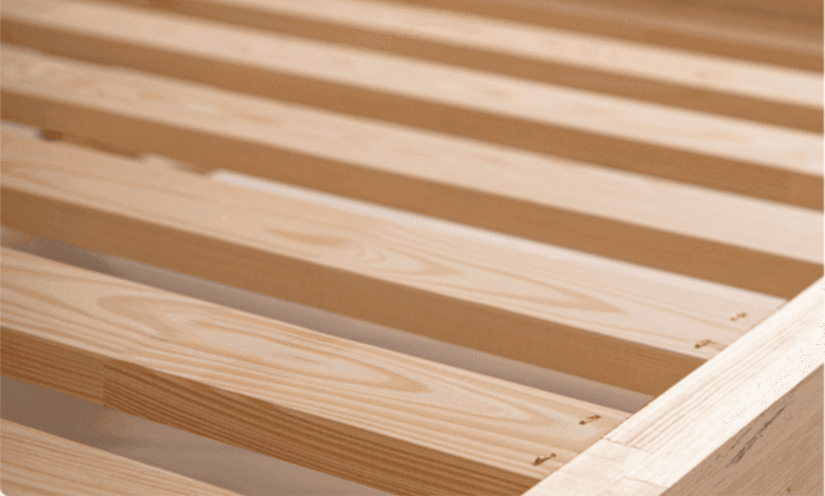 Primer plano de las lamas y el borde de madera maciza de la estructura de la cama