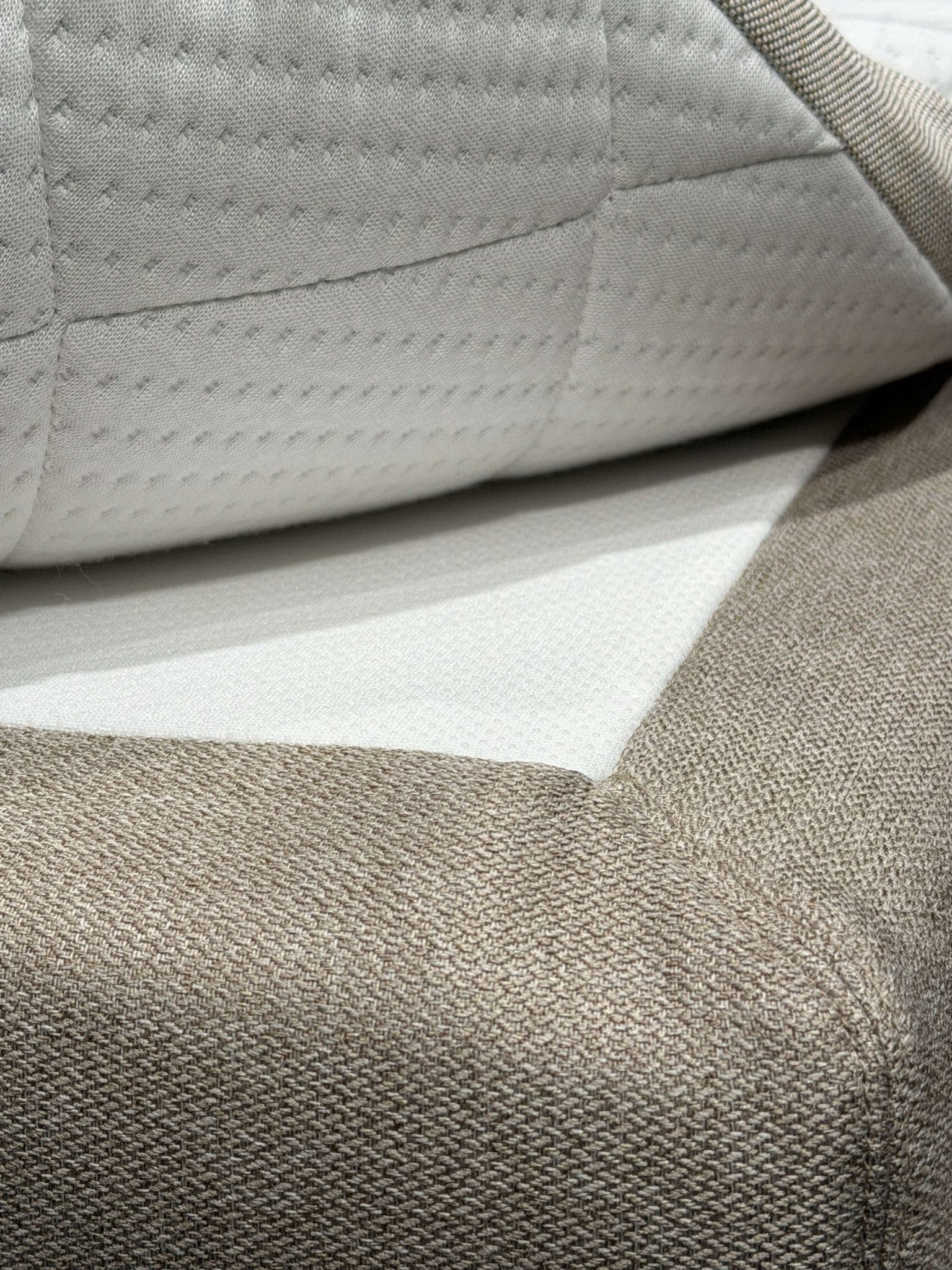 Corner of the mattress topper lifted to reveal the non-slip layer between the topper and bed cover