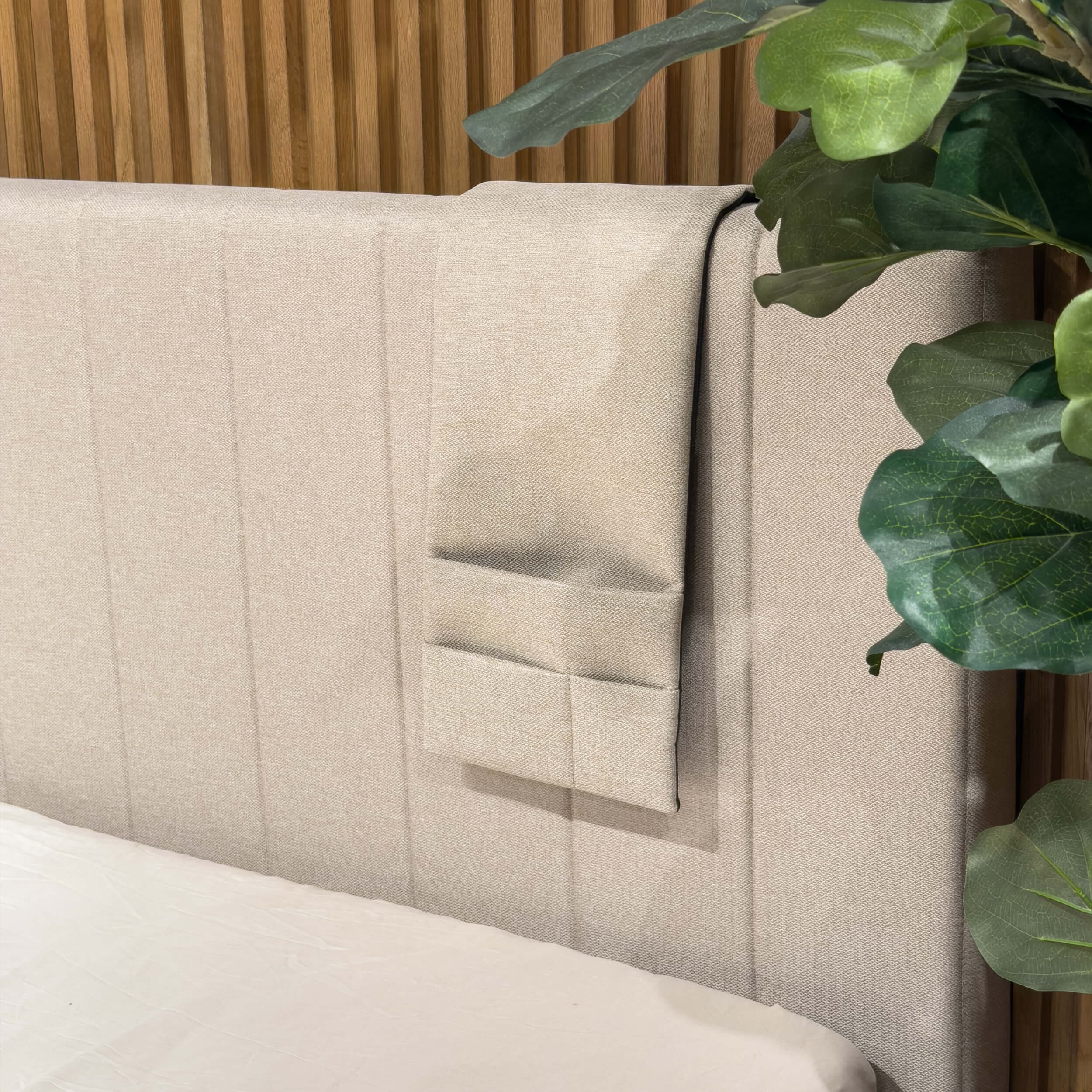Bolsillo de cama beige con tres compartimentos, colgado del borde del cabecero