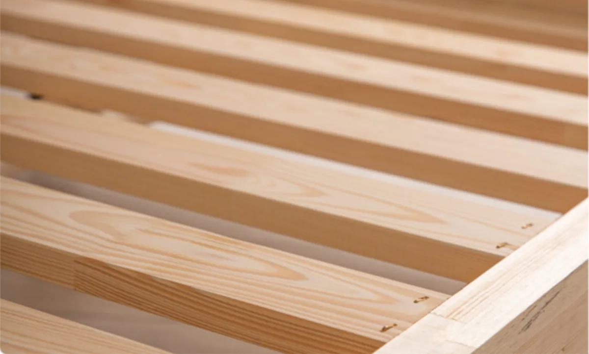 Primer plano de las lamas y el borde de madera maciza de la estructura de la cama