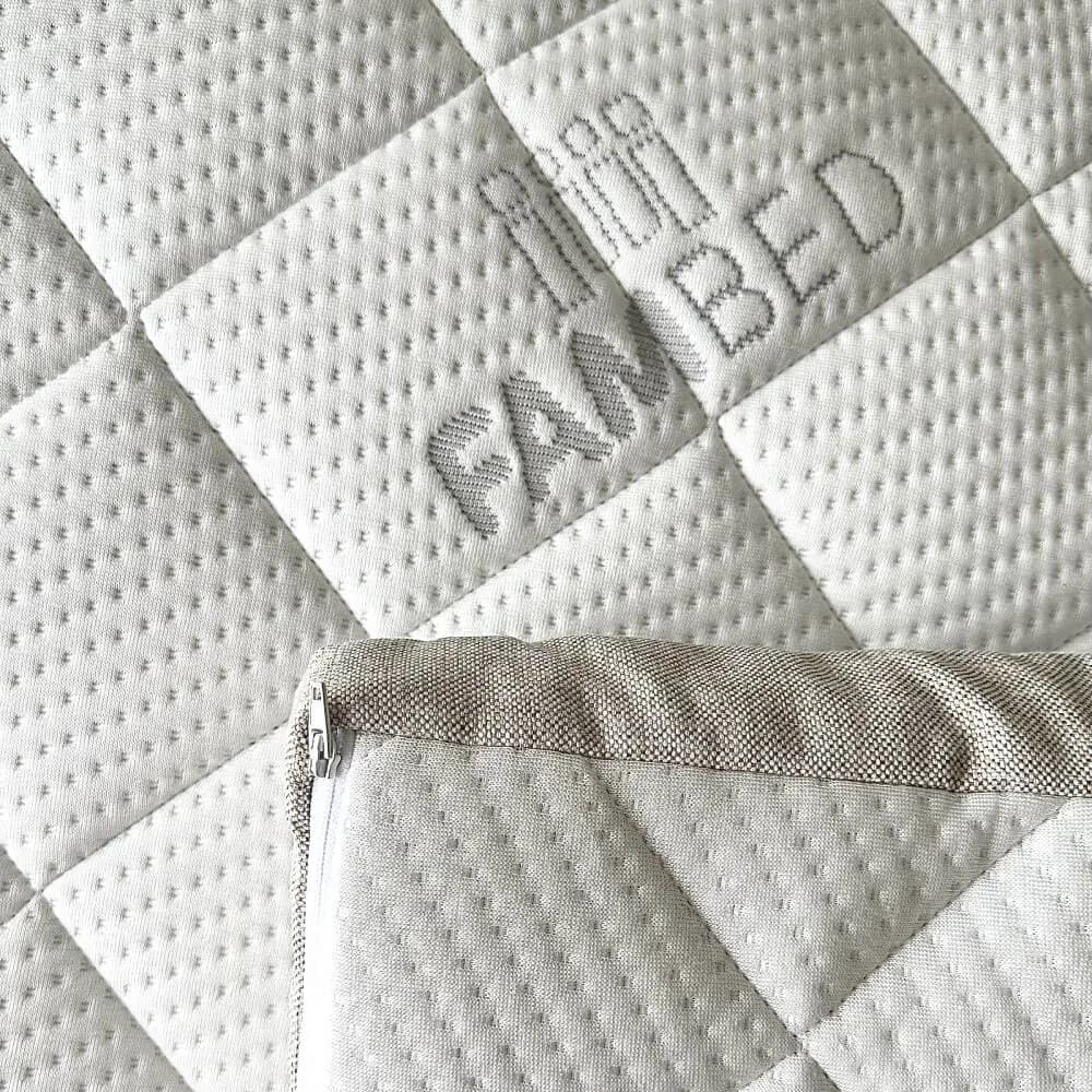 Close-up of the mattress topper's quilted white cover with a woven FAMBED logo